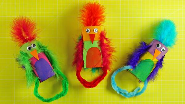 buntes Papageien-Armband aus einer Klopapierrolle, Federn und Pfeiffenreiniger | Rechte: KiKA